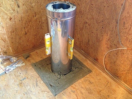 La photo montre l'installation d'une cheminée en acier inoxydable