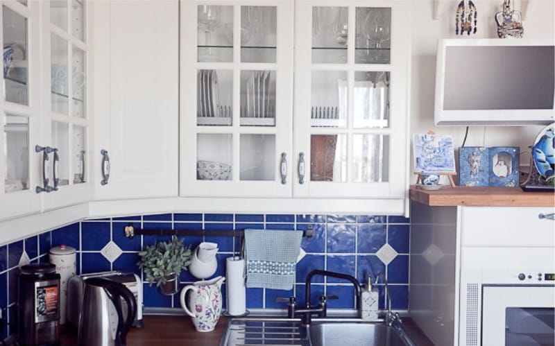 Interiér bielej a modrej kuchyne s riadom s gzhelskou maľbou