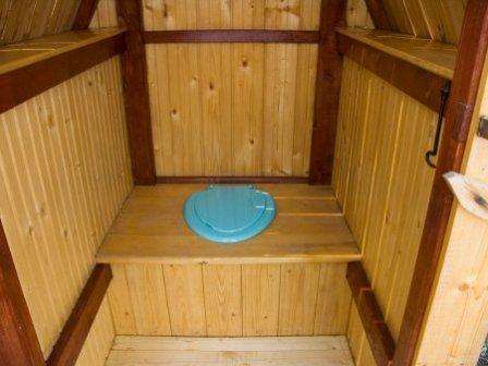 Le cadre du siège des toilettes est recouvert de planches. Ensuite, un trou est découpé pour la selle. Un seau est placé sous le siège des toilettes.